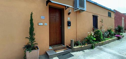 un bâtiment avec une porte marron et quelques plantes dans l'établissement Casa Debby, à Porto Torres