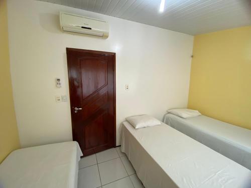2 camas en una habitación con puerta marrón en Residência Ximenes, en Fortaleza