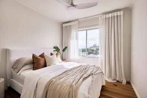 a white bedroom with a bed and a window at Sunsets at Epic Lennox Head in Lennox Head