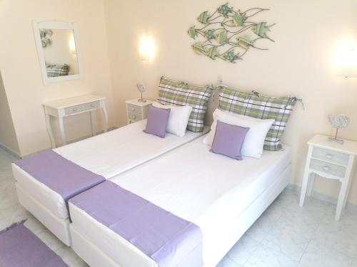a bedroom with a large white bed with purple pillows at Akrogiali in Skala