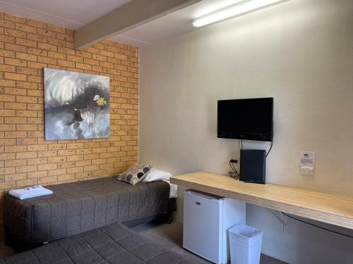a room with a bed and a flat screen tv at Citrus Motel in Griffith