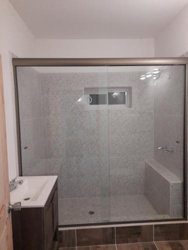 a bathroom with a glass shower with a sink at BAJA SUITES UPSTAIRS in Punta Abreojos
