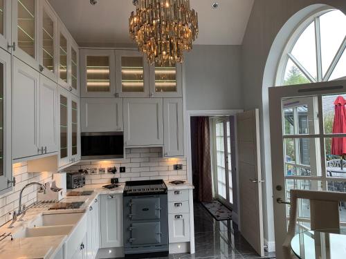 a kitchen with white cabinets and a chandelier at Little Fox Lodge Luxury Hideaway with Hot Tub Glencoe Near Fortwilliam in Glencoe