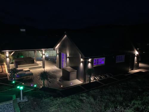 a house with a deck at night with lights at Little Fox Lodge Luxury Hideaway with Hot Tub Glencoe Near Fortwilliam in Glencoe
