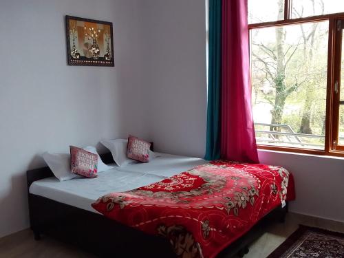 a bedroom with a bed with a red blanket and a window at Samaira home stay in Bīr