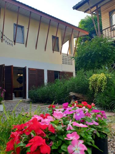 a bunch of flowers in front of a house at ฮักเคียงโขง HUG Khieng Khong Nongkhai Hostel in Nong Khai