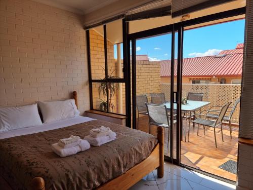 a bedroom with a bed and a balcony with a table at Tuggeranong Short Stay #10 - Sleeps 6 in Tuggeranong