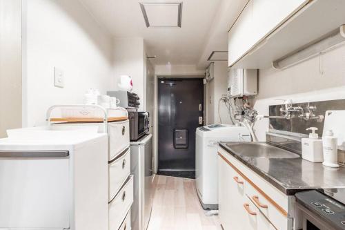 a kitchen with white appliances and a black door at HIDEOUT in Sapporo