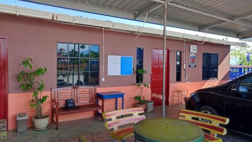 a table and chairs outside of a pink building at Taun Gusi Village Homestay in Kota Belud