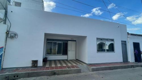 a white house with a porch on a street at Alojamiento Mamá Juana in Ríohacha