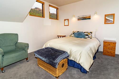 een slaapkamer met een bed en een groene stoel bij Arrow Getaway - Arrowtown Holiday Home in Arrowtown