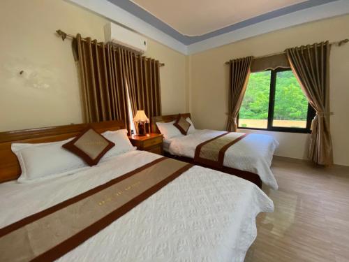 Habitación de hotel con 2 camas y ventana en Phong Nha Orient Hotel en Phong Nha