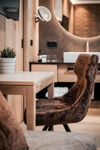 a chair sitting next to a wooden table with a desk at Seehotel Panorama Relax in Resia