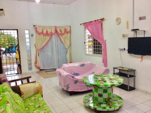 a living room with a pink bed and a table at Addeen homestay in Kemaman