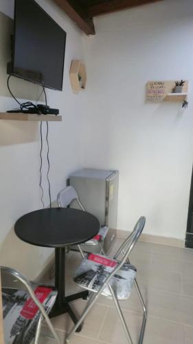 una mesa y sillas con TV en la pared en HABITACION AMOBLADA SECTOR LAURELES-ESTADIO hasta 3 personas Santorini, en Medellín