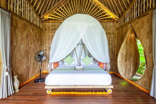a bedroom with a bed in a tent at Balikayanas Bamboo House - Miggiell House in Karangasem