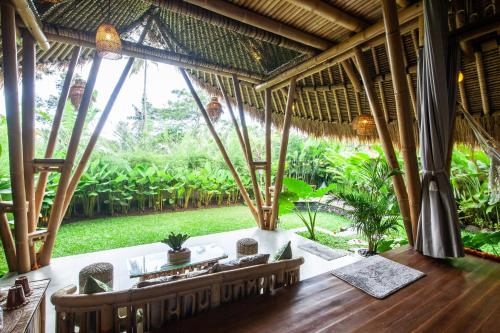 an outdoor dining room with a view of a garden at Balikayanas Bamboo House - Miggiell House in Karangasem