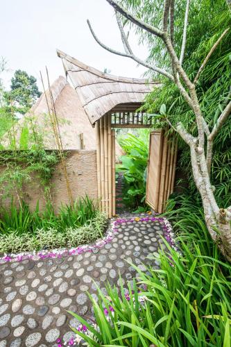 a garden with a walkway leading to a building at Balikayanas Bamboo House - Miggiell House in Karangasem