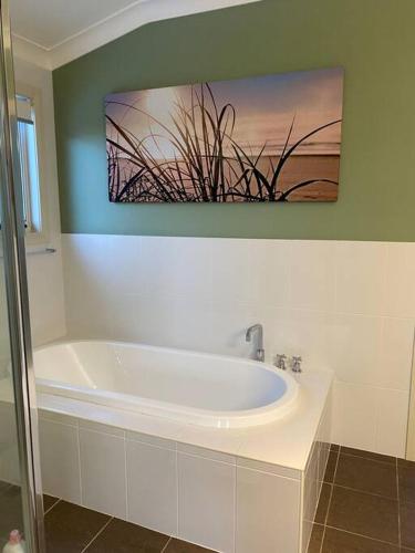 a bathroom with a white tub and a painting on the wall at Ocean View Oasis, Coffs Harbour in Coffs Harbour