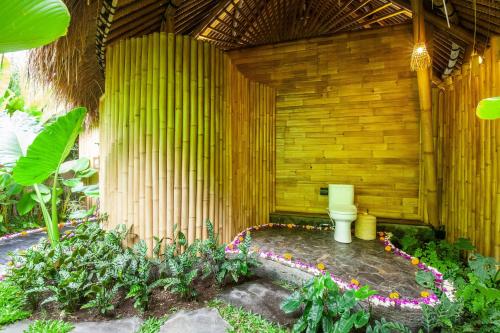 a garden with a toilet in a wooden wall at Balikayanas Bamboo House - Miggiell House in Karangasem