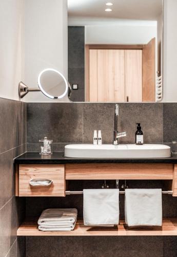a bathroom with a sink and a mirror at Seehotel Panorama Relax in Resia