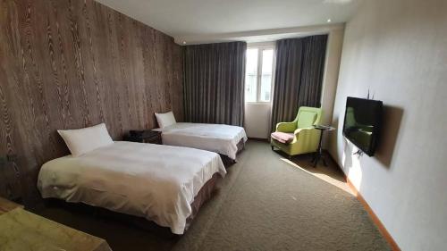 a hotel room with two beds and a flat screen tv at Chia Shih Pao Hotel in Taibao