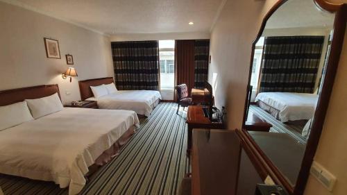 a hotel room with two beds and a mirror at Chia Shih Pao Hotel in Taibao