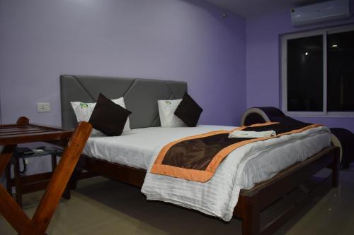 a bedroom with a bed with a wooden frame and a window at HOTEL PURI GREENS in Puri