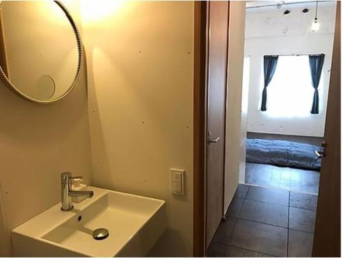 a bathroom with a sink and a mirror and a bedroom at ゴールデンマイルホステル３Ｆ完全個室Aタイプ in Amami