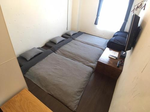 a small bedroom with a bed and a desk at ゴールデンマイルホステル３Ｆ完全個室Aタイプ in Amami