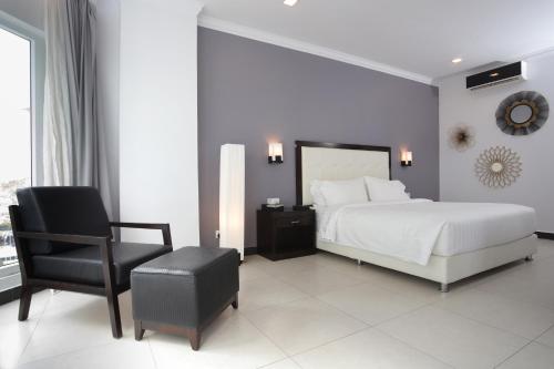 a bedroom with a white bed and a chair at Queenco Hotel & Casino in Sihanoukville