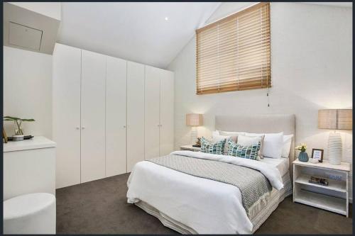 um quarto branco com uma cama e uma janela em Lonnie Beach View Apartment em Point Lonsdale