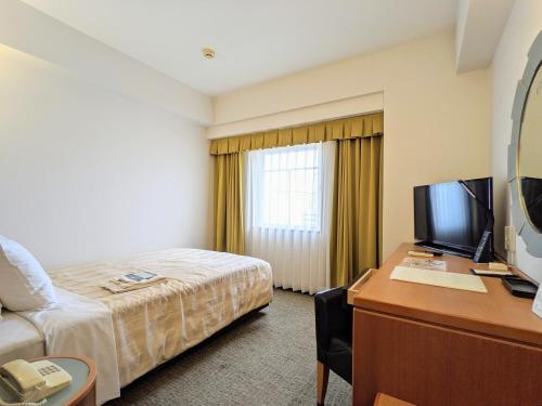 a hotel room with a bed and a desk with a computer at GRG Hotel Naha Higashimachi in Naha