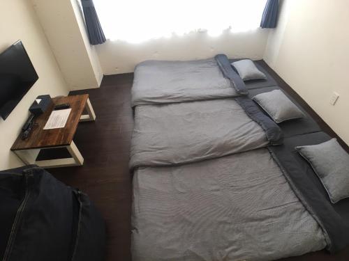 a small bedroom with two beds and a table at ゴールデンマイルホステル３Ｆ完全個室Ｂタイプ in Amami