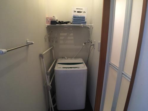 a small bathroom with a washer and dryer at ゴールデンマイルホステル３Ｆ完全個室Ｂタイプ in Amami