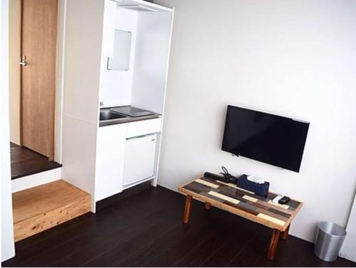 a living room with a tv and a coffee table at ゴールデンマイルホステル３Ｆ完全個室Ｂタイプ in Amami