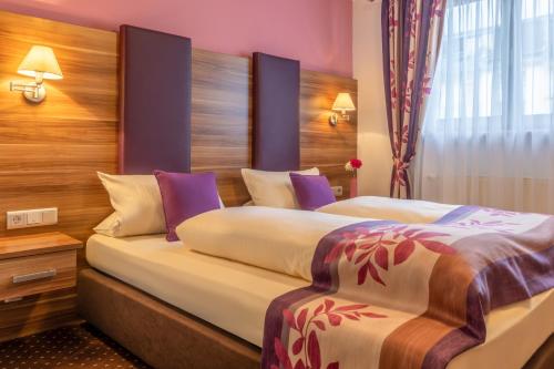 リューデスハイム・アム・ラインにあるアルトドイチェ ヴァインシュトゥーベ スーペリアの紫の壁のホテルルーム内のベッド2台
