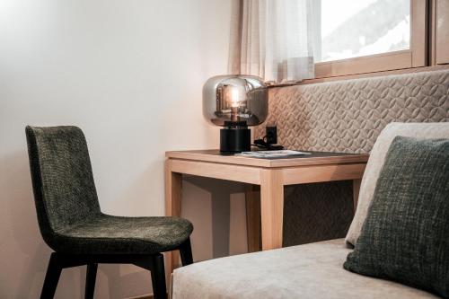 a bedroom with a desk and a chair and a lamp at Seehotel Panorama Relax in Resia