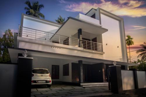 a white house with a car parked in front of it at Bachan's Casa in Cherai Beach