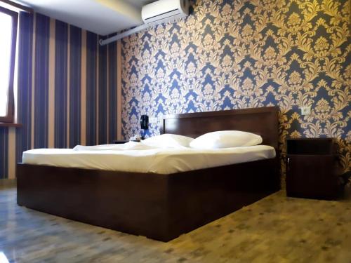 uma cama num quarto com papel de parede azul e dourado em Green Garden Hotel em Yerevan