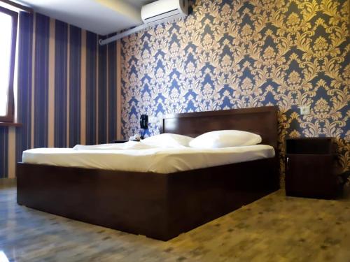 a bed in a bedroom with a blue and gold wallpaper at Green Garden Hotel in Yerevan