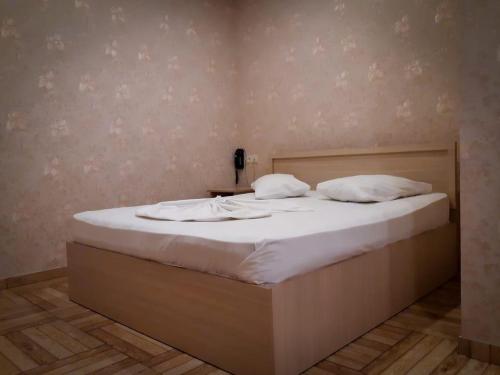 a bed with white sheets and pillows on it at Green Garden Hotel in Yerevan