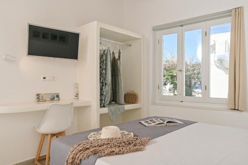 a white bedroom with a bed and a tv on the wall at Venetian Suites III in Naxos Chora