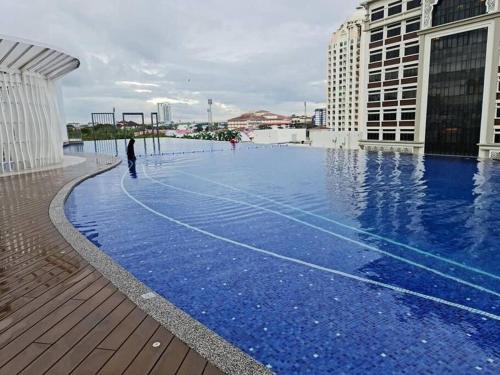 哥打巴魯的住宿－Lovely 2-BR service apartment with pool (melur @ troikaKB)，一个人站在游泳池边