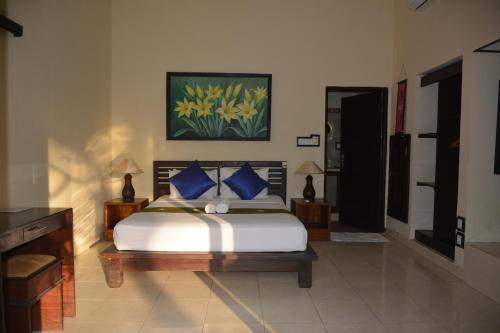 a bedroom with a large bed with blue pillows at Segara Wangi Beach Cottages in Candidasa