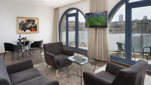 a living room with a tv and chairs and a table at Leonardo Hotel Jerusalem in Jerusalem