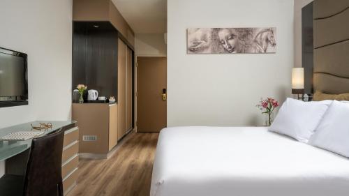 a hotel room with a white bed and a desk at Leonardo Hotel Jerusalem in Jerusalem