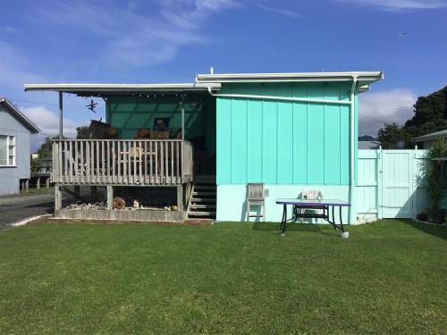 a green house with a dog sitting on a deck at Beach Belle in Bowentown
