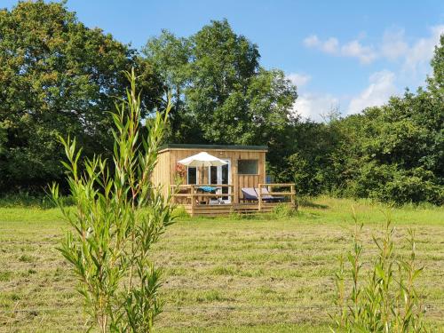 a small wooden cabin in a field with trees at Dartmoor Reach Alpaca Farm Heated Cabins in Bovey Tracey