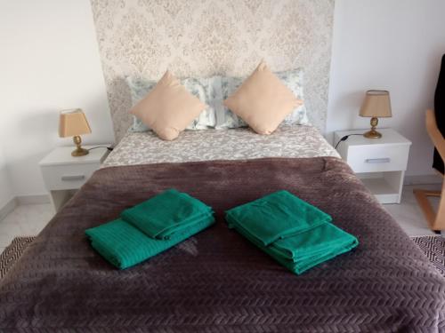 Una cama con dos almohadas verdes encima. en Peniche Waves, en Peniche